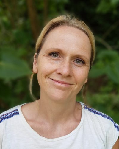 Porträt von Karolin Graichen vor grünem Laub.